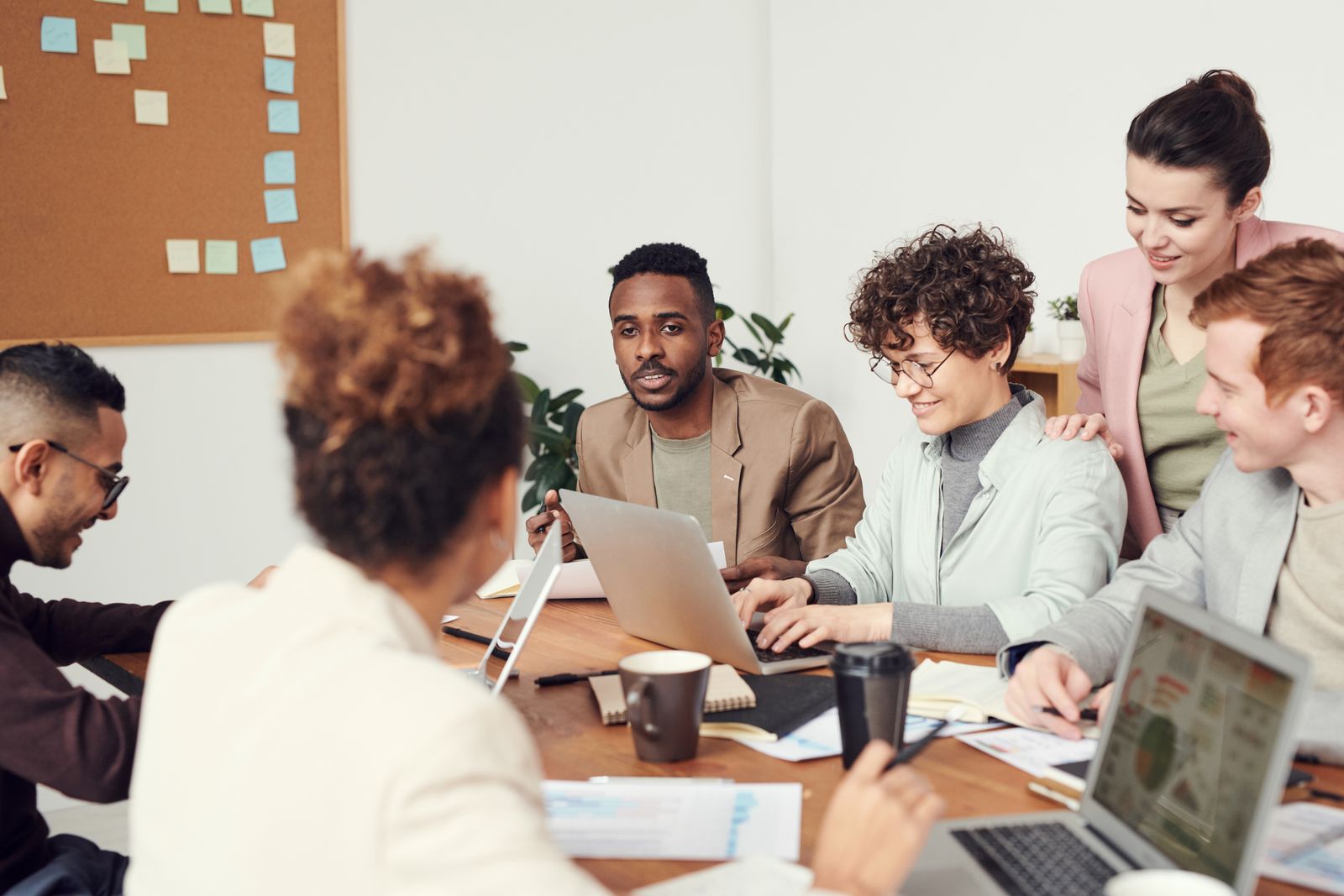 A team meeting around a table with laptops and notes